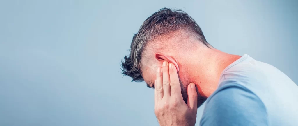 man with tinnitus holding his ear