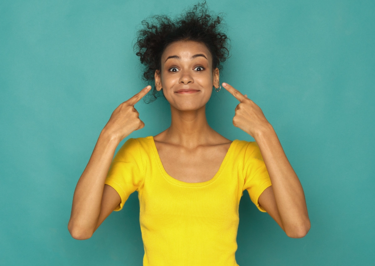 Happy woman pointing to her ears that have ear wax