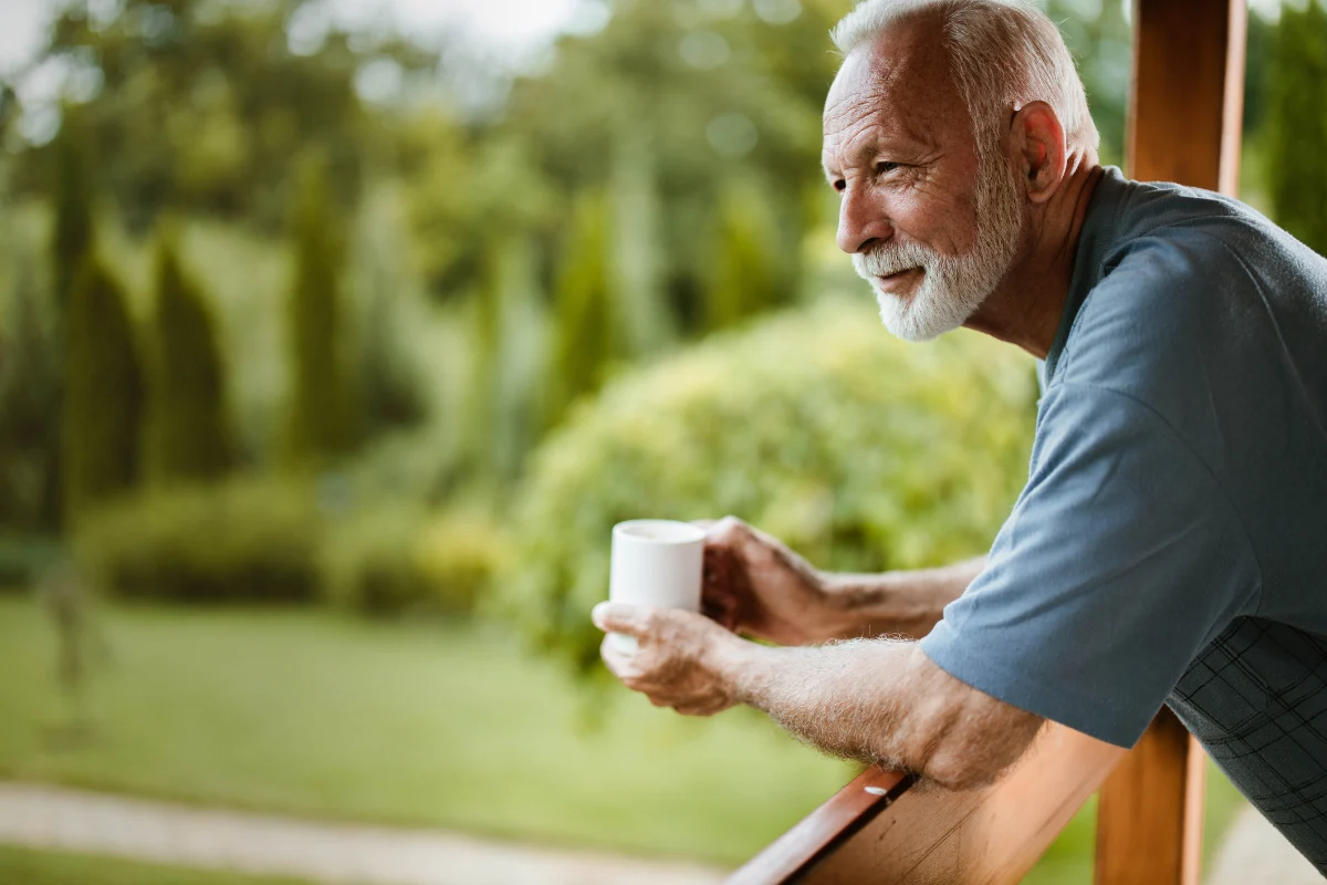 man wearing hearing aids leaning against verandar