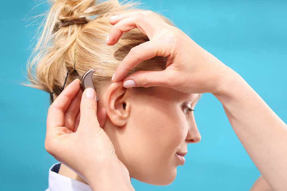 man wearing hearing aids leaning against verandar