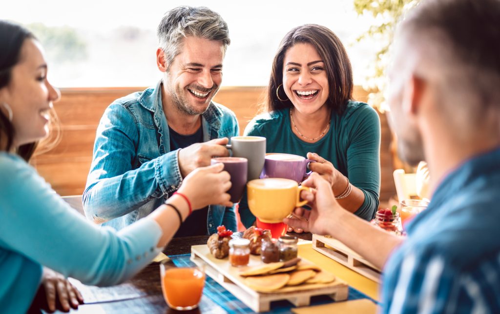 People group toasting latte at coffee bar rooftop – Friends talking and having fun together at cappuccino restaurant – Life style concept with happy men and women at cafe terrace – Bright warm filter