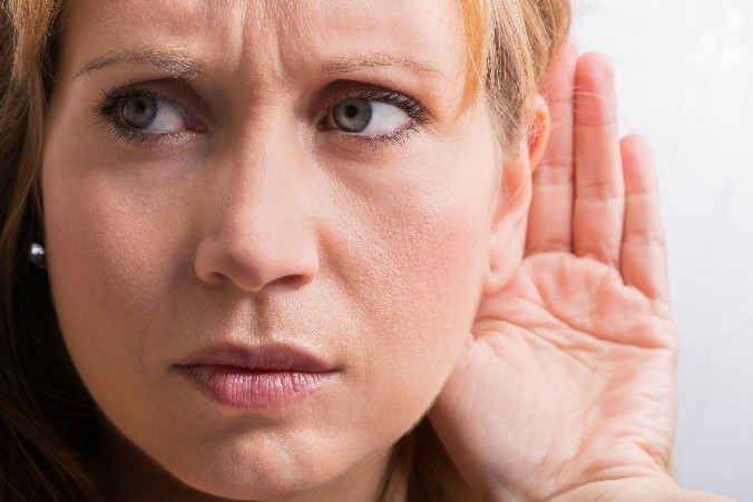 Woman with hand to ear trying to hear